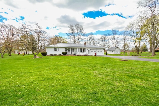 view of front of home featuring a front lawn, aphalt driveway, a chimney, an attached garage, and a porch