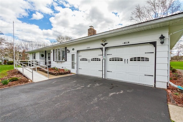 exterior space featuring an attached garage, driveway, and a chimney