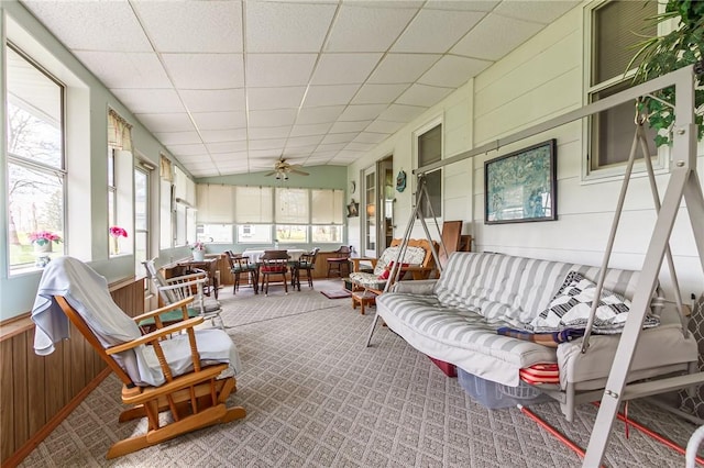 sunroom / solarium with ceiling fan, wainscoting, wood walls, outdoor lounge area, and carpet