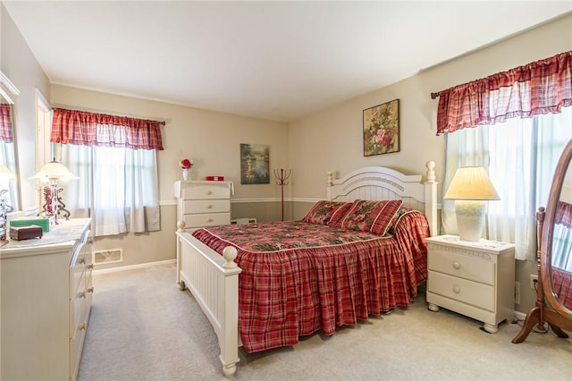 bedroom with baseboards, visible vents, and light colored carpet