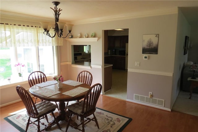 dining room with crown molding, a notable chandelier, visible vents, and plenty of natural light