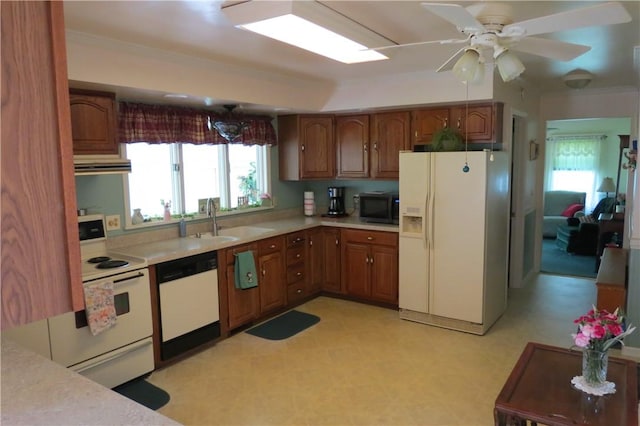 kitchen featuring white appliances, light floors, light countertops, brown cabinets, and a sink