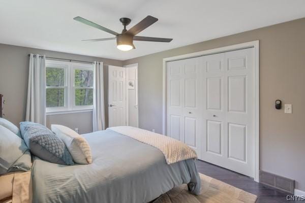 bedroom featuring a closet, baseboards, ceiling fan, and wood finished floors