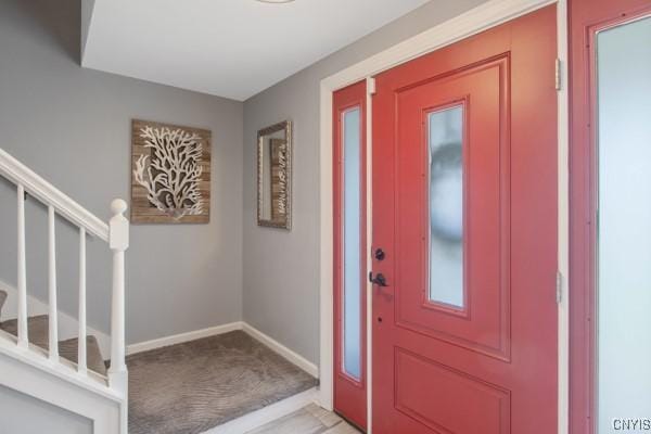 entryway with baseboards, light carpet, and stairs