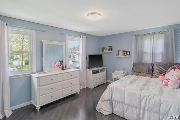 bedroom with baseboards and dark wood-type flooring