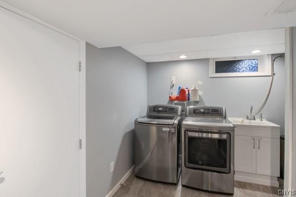 laundry room featuring baseboards, separate washer and dryer, a sink, cabinet space, and light wood finished floors