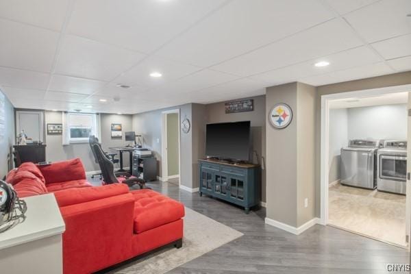 living area with washing machine and clothes dryer, a paneled ceiling, recessed lighting, baseboards, and wood finished floors