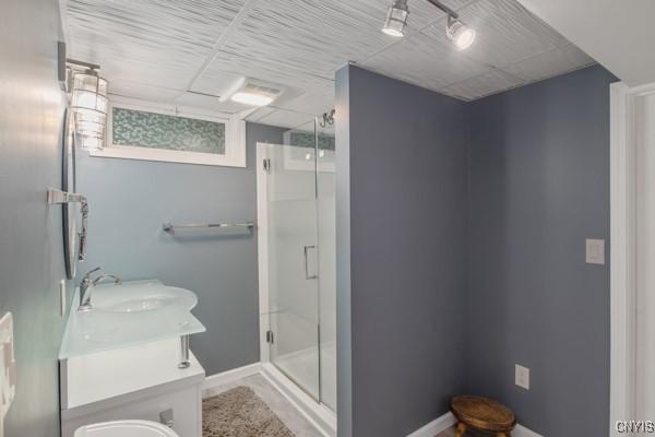 bathroom featuring vanity, baseboards, and a shower stall