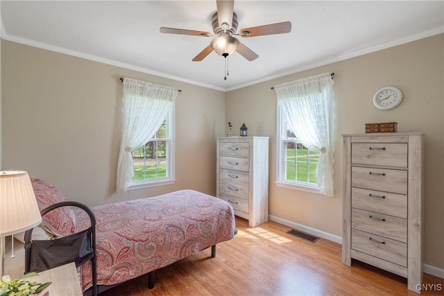 bedroom featuring multiple windows, ornamental molding, and light wood finished floors