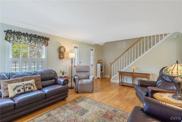 living area with ornamental molding, wood finished floors, and stairway