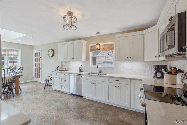 kitchen featuring white cabinets, appliances with stainless steel finishes, a sink, light countertops, and backsplash