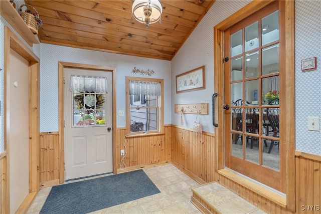doorway to outside with wooden walls, wainscoting, wallpapered walls, and lofted ceiling