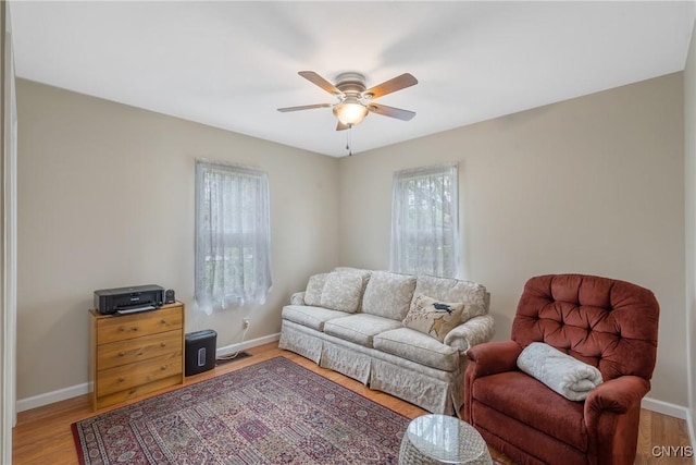 living room featuring light wood-style floors, a ceiling fan, and baseboards