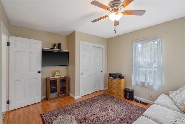 living room with baseboards, ceiling fan, visible vents, and wood finished floors
