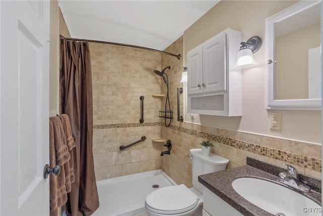 bathroom featuring vanity, toilet, tiled shower, and tile walls