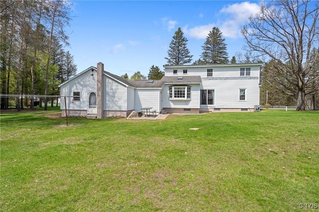 rear view of house with a lawn, a chimney, entry steps, and a patio area