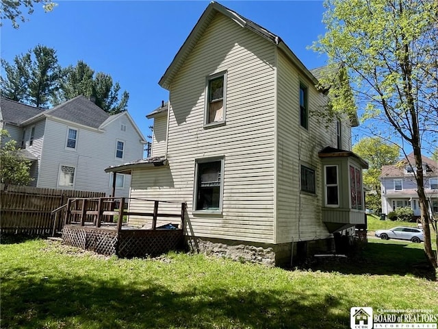 rear view of property featuring a yard, fence, and a wooden deck