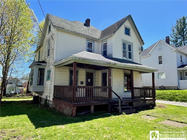 view of front of home featuring covered porch, a chimney, and a front yard