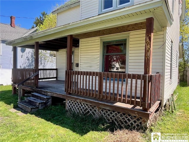 view of exterior entry with a lawn and covered porch