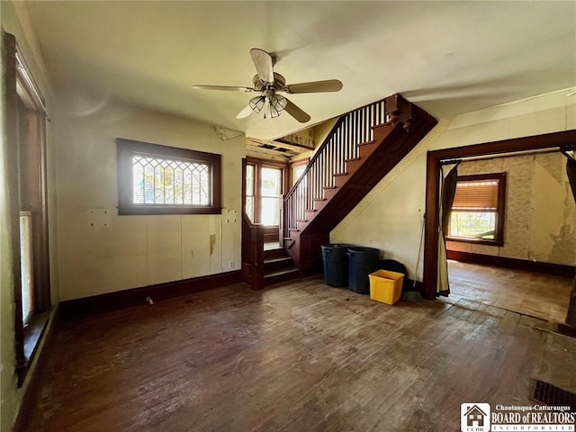 unfurnished living room featuring baseboards, ceiling fan, wood finished floors, and stairway