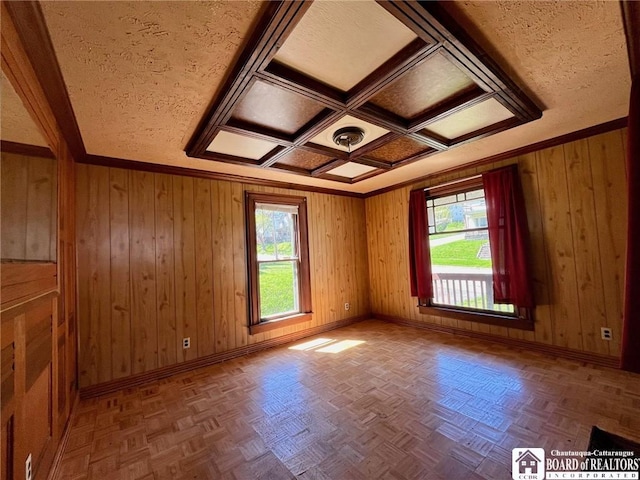 spare room with crown molding, baseboards, and wood walls