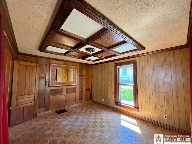 spare room with baseboards, wood walls, and a textured ceiling