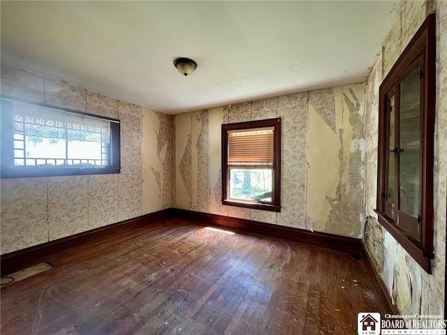 unfurnished room with baseboards, wallpapered walls, plenty of natural light, and wood finished floors