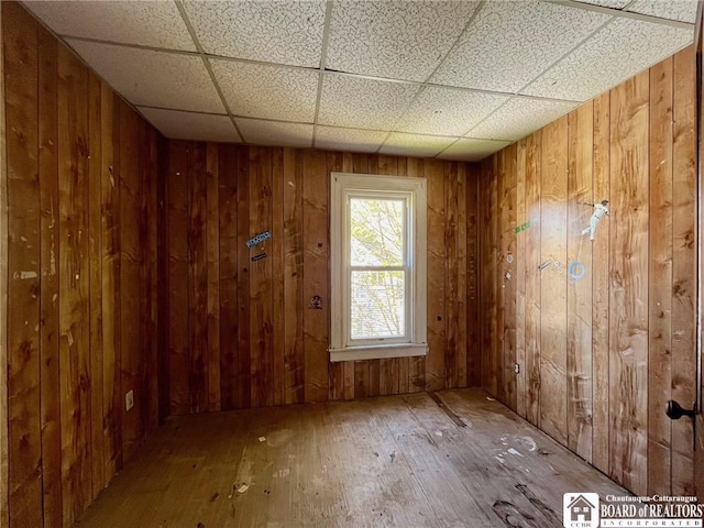 spare room featuring wood-type flooring, wood walls, and a paneled ceiling
