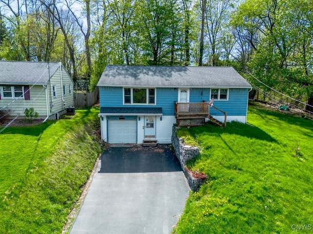 view of front of house featuring aphalt driveway, a wooden deck, a garage, cooling unit, and a front lawn