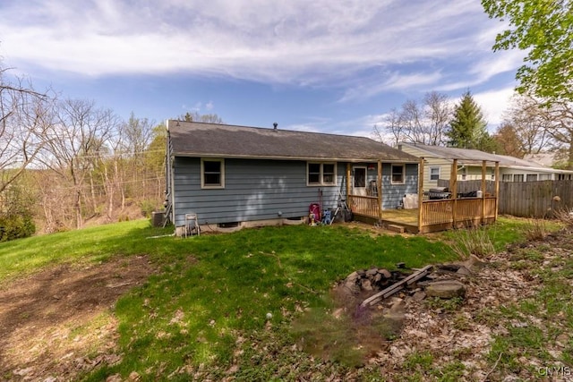 rear view of house featuring a lawn, fence, central AC unit, and a deck