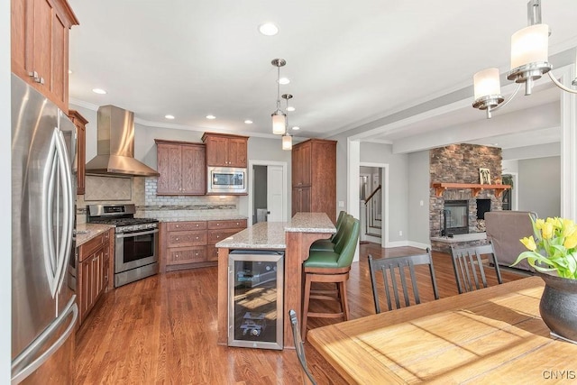 3830 Rippleton Rd, Cazenovia, NY 13035 - kitchen featuring wall chimney range hood, a fireplace, beverage cooler, brown cabinetry, and stainless steel appliances