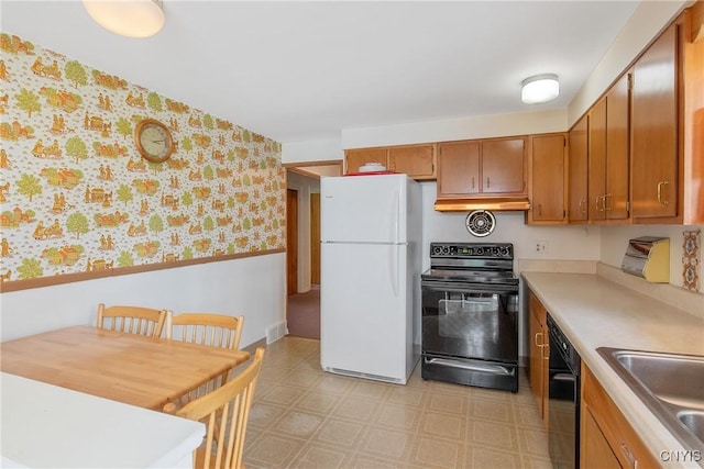 kitchen with dishwasher, light countertops, black electric range, freestanding refrigerator, and wallpapered walls