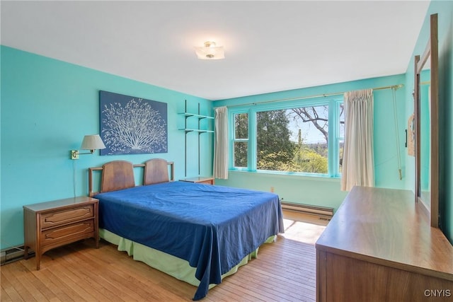 bedroom with baseboard heating and hardwood / wood-style floors