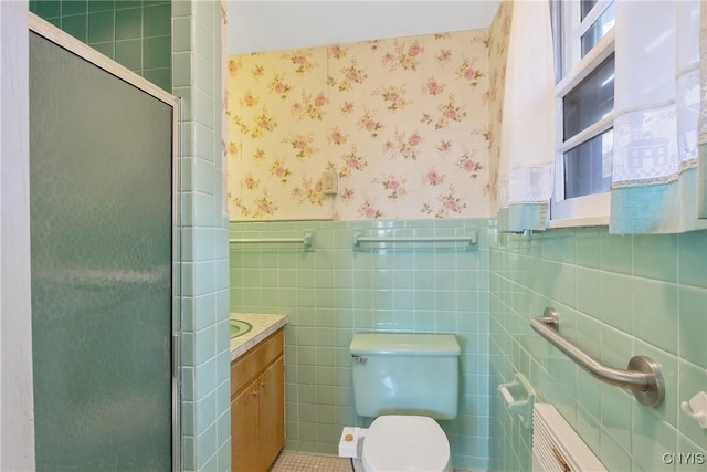 bathroom featuring a shower stall, wainscoting, tile walls, and wallpapered walls