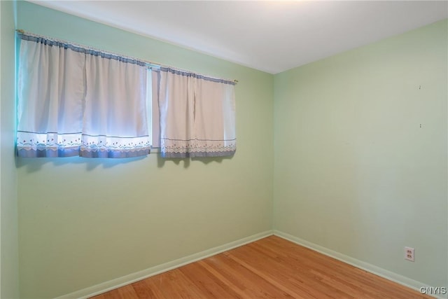 unfurnished room with baseboards and wood finished floors