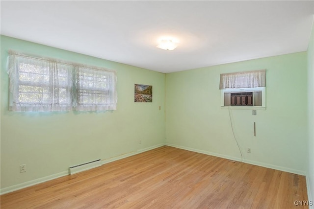 empty room featuring wood finished floors, baseboards, a baseboard heating unit, and cooling unit