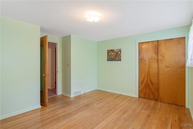 unfurnished bedroom with baseboards, a closet, light wood-style flooring, and visible vents