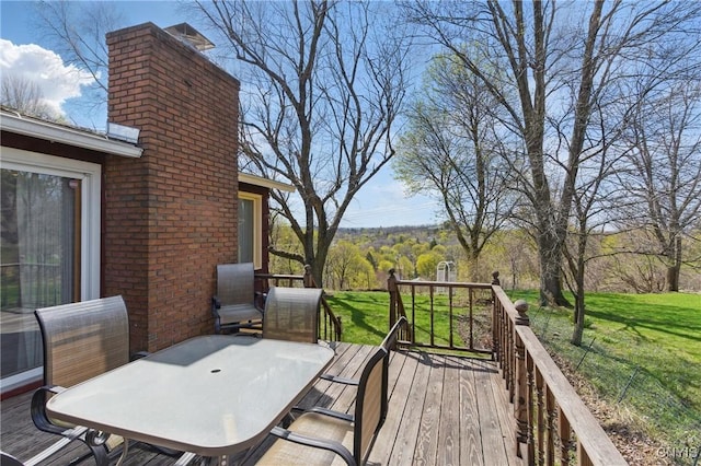 wooden terrace featuring outdoor dining area and a lawn