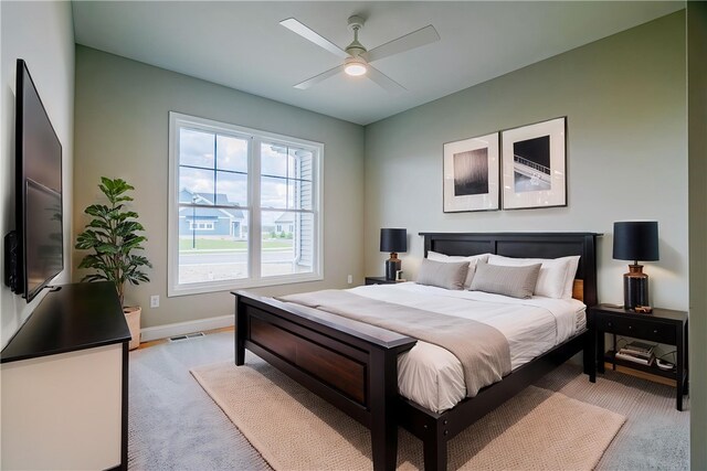 bedroom with baseboards, a ceiling fan, visible vents, and light carpet