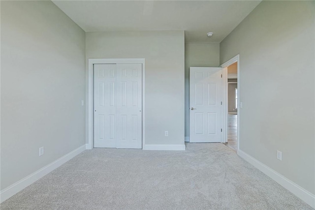 unfurnished bedroom featuring baseboards, carpet, and a closet