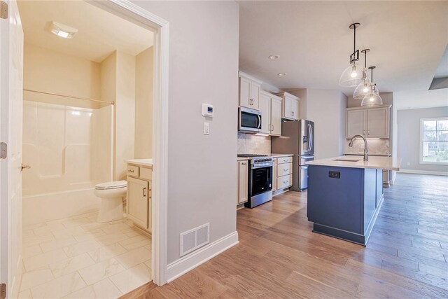 kitchen with visible vents, light countertops, tasteful backsplash, a sink, and appliances with stainless steel finishes