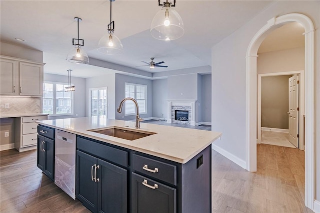 kitchen with light wood-type flooring, a sink, ceiling fan, and dishwasher