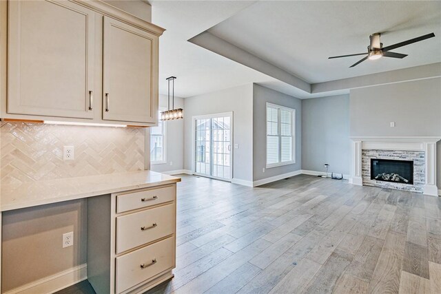 kitchen featuring decorative backsplash, baseboards, open floor plan, light wood-style floors, and ceiling fan