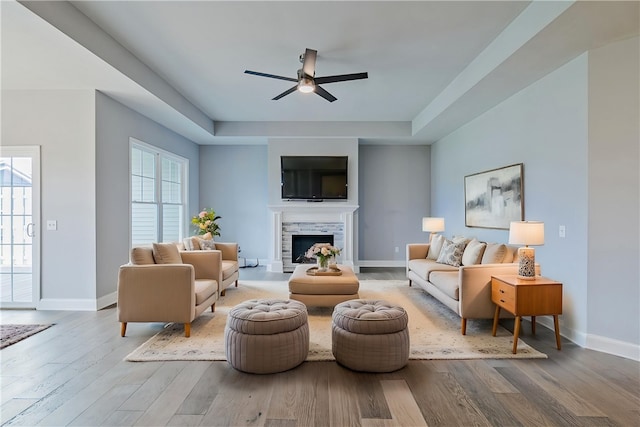 living area featuring baseboards, a fireplace, a ceiling fan, and wood finished floors