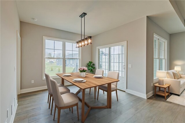 dining area with light wood-style floors, baseboards, and an inviting chandelier