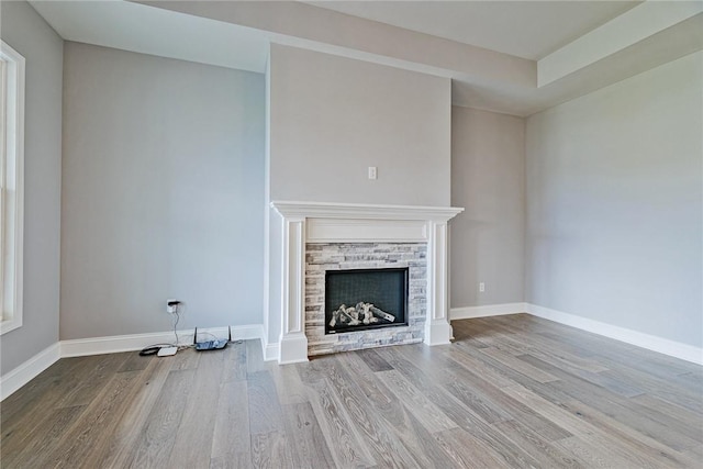 unfurnished living room with baseboards, a fireplace, and wood finished floors