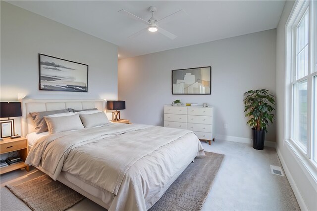 bedroom with a ceiling fan, baseboards, visible vents, and light carpet