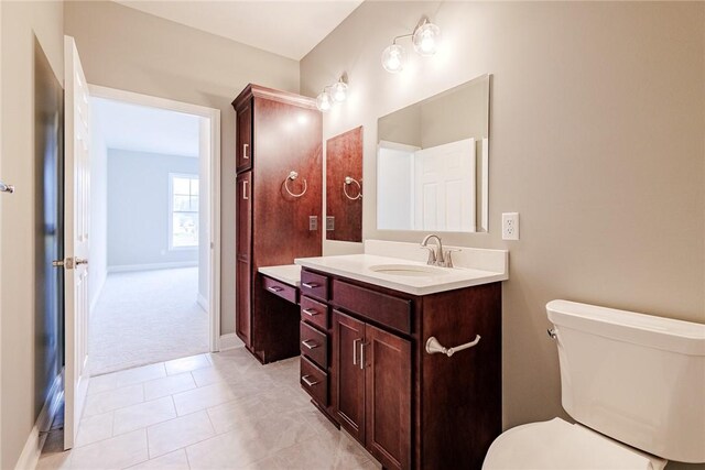 bathroom with vanity, baseboards, tile patterned floors, and toilet