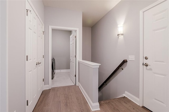 corridor featuring baseboards, an upstairs landing, and wood finished floors