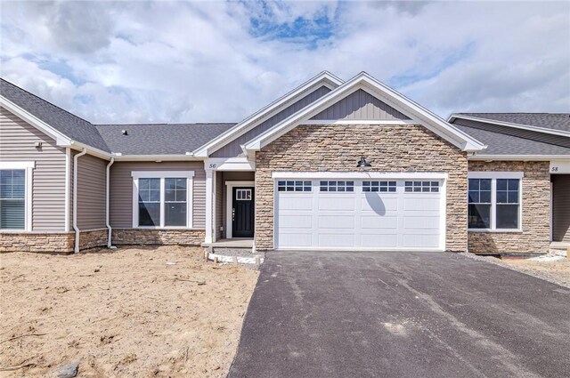 view of front facade featuring an attached garage, board and batten siding, driveway, and stone siding